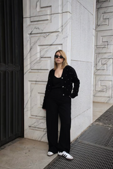 a lady in a black v-neck rhinestone knitted cardigan with black pants